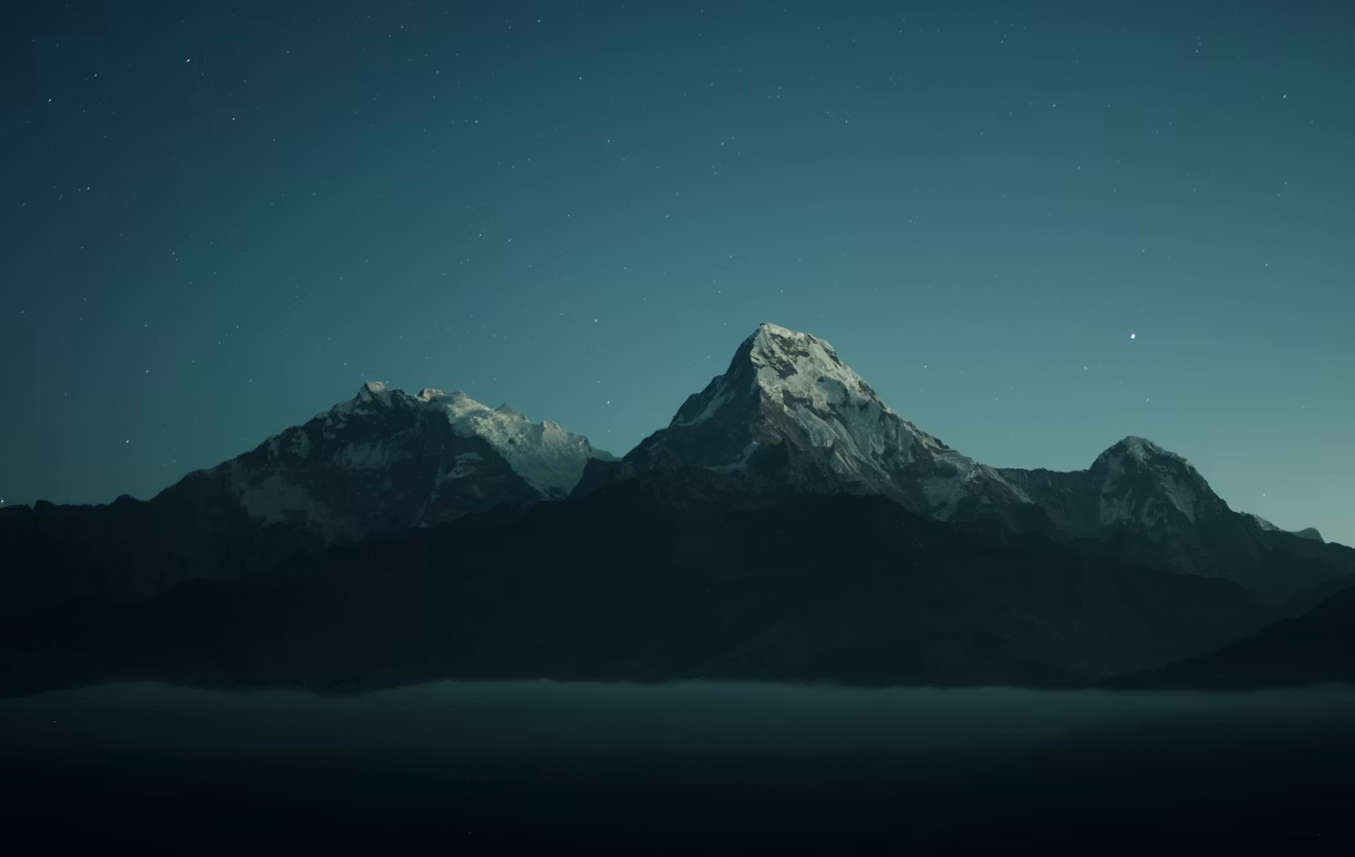 Snow-capped mountains under a starlit night sky